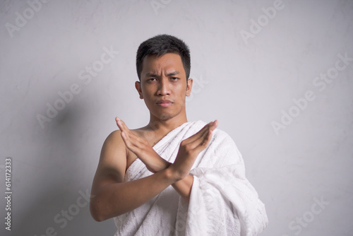 Asian muslim man wearing white ihram clothes show crossed hands
