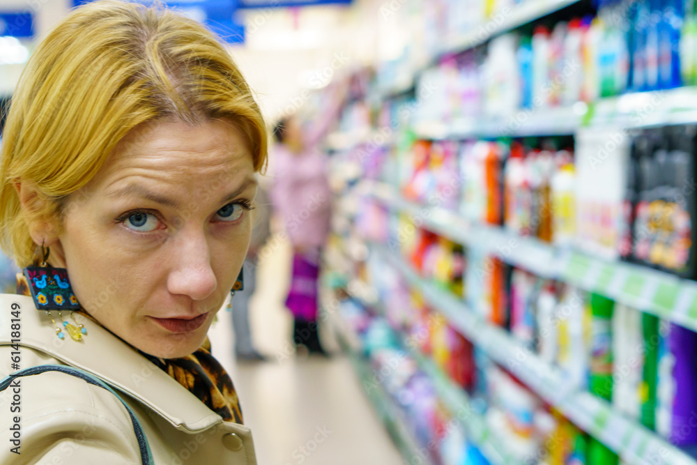 Grodno, Belarus June 21, 2023: A girl buyer in a non-food store examines the goods and makes purchases. Visitors at the mall. Grodno, Belarus June 21, 2023: A girl buyer in a non-food store examines the goods and makes purchases. Visitors at the mall.