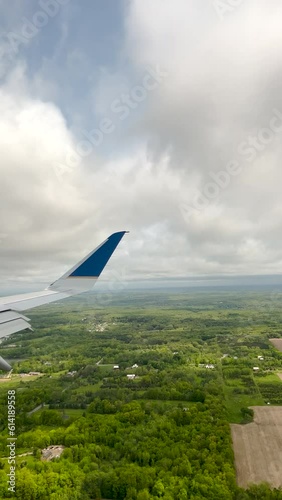 Airplane flies low over a lush green landscape, descending to land on the airport landing strip at Gerald Ford International Airport in Grand Rapids, Michigan, USA. Passenger point of view. photo