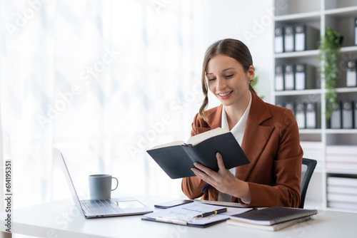 Beautiful young business woman manager or company worker holding accounting document, checking financial data or marketing report working in office with laptop. Accountant consults on some document.