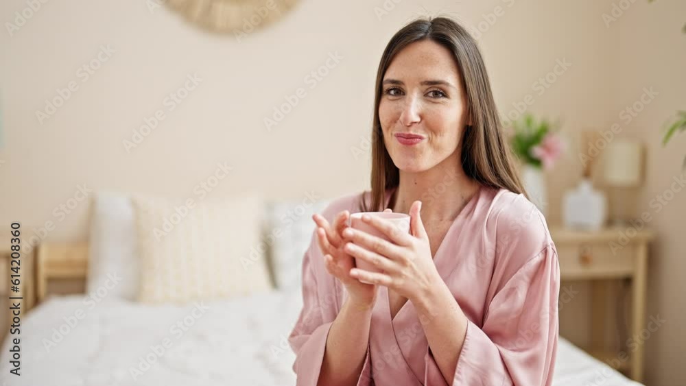 Young beautiful hispanic woman drinking cup of coffee sitting on bed at bedroom Young beautiful hispanic woman drinking cup of coffee sitting on bed at bedroom
