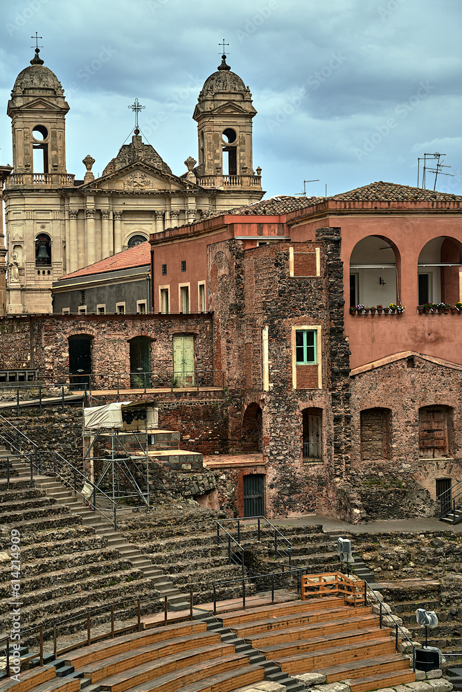 Ancient greek theater ruins, historic townhouses and baroque bell towers of a church in the city of Catania