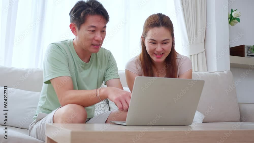 Young asian couple using laptop computer for looking social media or video with relax and leisure on sofa in the living room at home, man and woman watching laptop online, lifestyles concept. Young asian couple using laptop computer for looking social media or video with relax and leisure on sofa in the living room at home, man and woman watching laptop online, lifestyles concept.