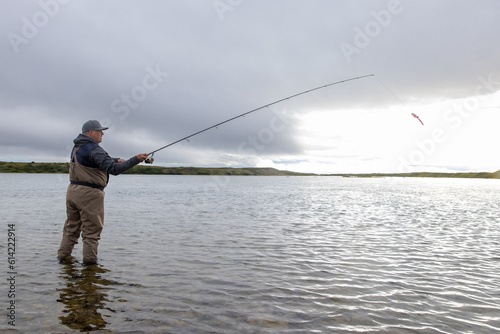 Fisherman casting his lure out to catch salmon in a river in Alaska