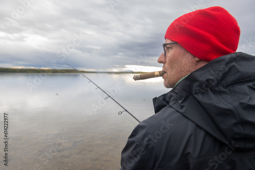 Fisherman smoking a cigar waiting to catch a fish with his fishing pole