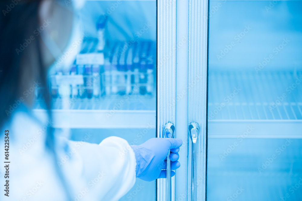 Close up scientist hand wear blue gloves opening storage reagent container for laboratory analysis.Medical technician working in biotechnological laboratory. Close up scientist hand wear blue gloves opening storage reagent container for laboratory analysis.Medical technician working in biotechnological laboratory.