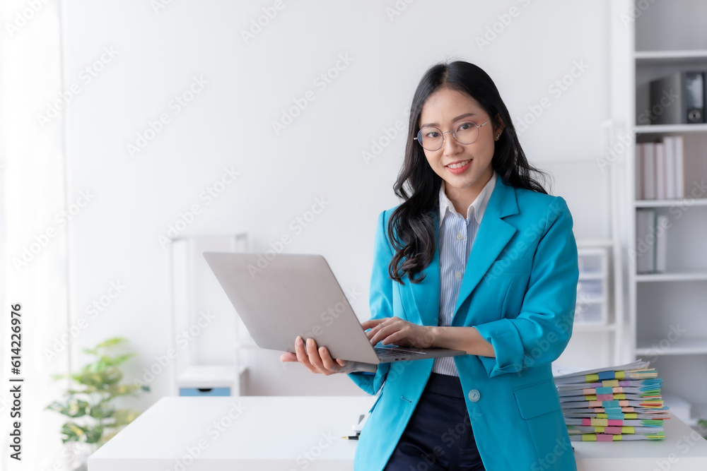 Happy smiling Asian businesswoman using laptop computer in the office. Beautiful young Asian female shopping or chatting online in social networks, freelance working on laptop projects. Happy smiling Asian businesswoman using laptop computer in the office. Beautiful young Asian female shopping or chatting online in social networks, freelance working on laptop projects.