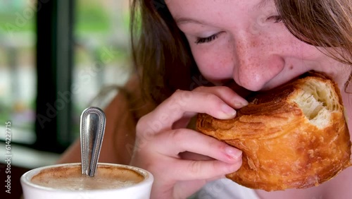 Woman tear of piece of tasty fresh croissant, closeup shot of hands. Lady eat snack at cafe, sun light fall from beside. High quality 4k footage photo