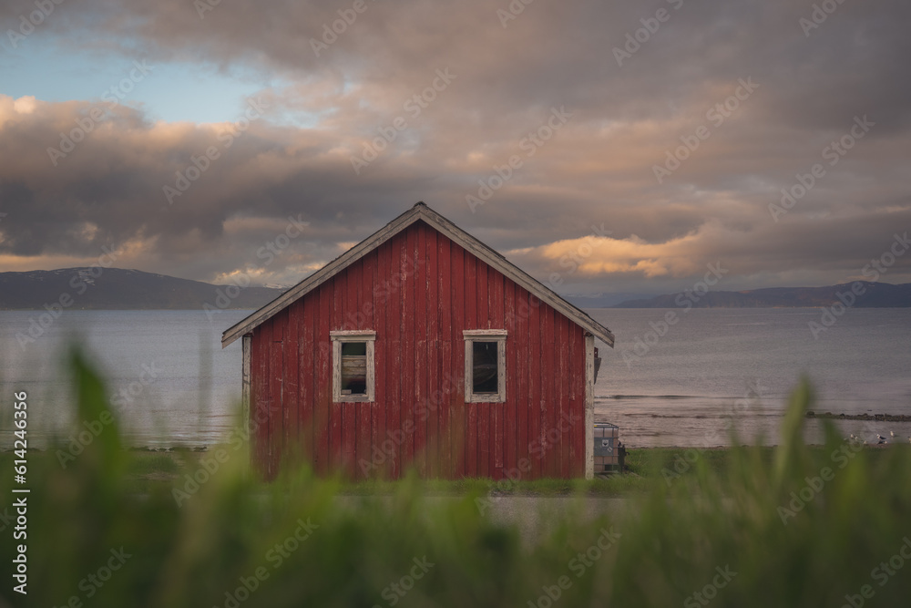 Red cottage of the Norwegian culture and architecture in Norway, with dynamic sunset sky