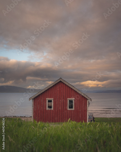 Red cottage of the Norwegian culture and architecture in Norway, with dynamic sunset sky