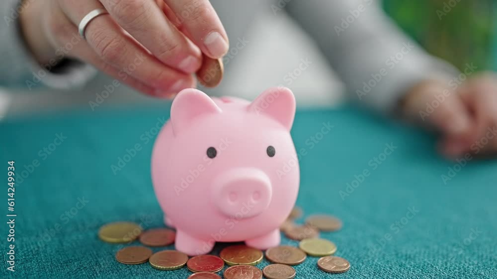 Hispanic man inserting coin on piggy bank at dinning room