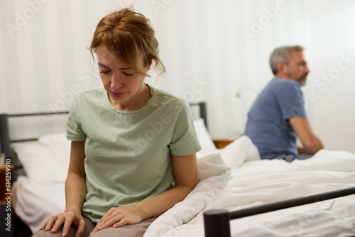 Couple sitting on different sides of bed not talking after argument