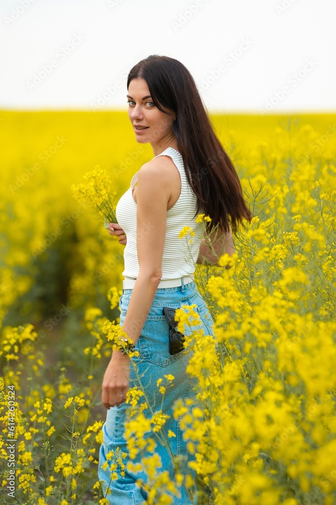 Happy beautiful woman walking on the field with yellow flowers Happy beautiful woman walking on the field with yellow flowers