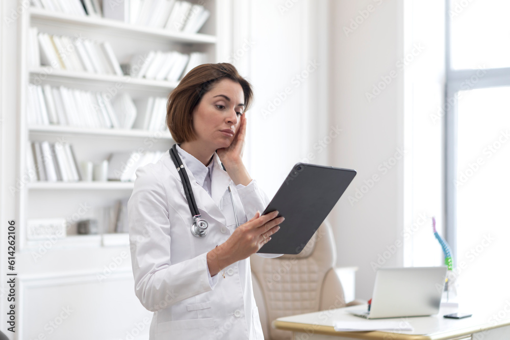 Side view on female physician standing and holding gadget and documents of patients. Modern health care concept Side view on female physician standing and holding gadget and documents of patients. Modern health care concept