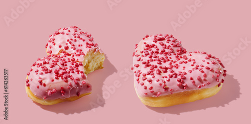 Bitten heart shaped donut with glaze on pink pastel background