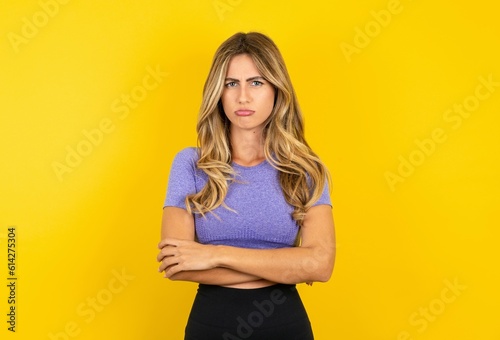 young beautiful blonde woman wearing sportswear over yellow studio background depressed and worry for distress, crying angry and afraid. Sad expression.