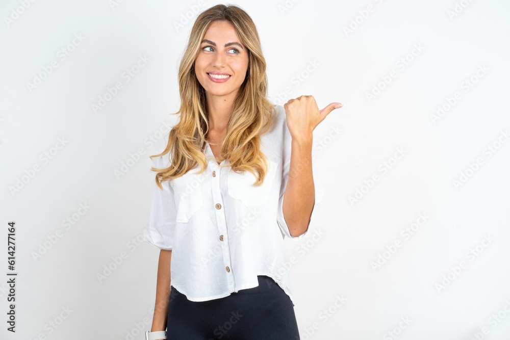 Charming young beautiful woman wearing white shirt over white studio background looking at copy space having advertisements Charming young beautiful woman wearing white shirt over white studio background looking at copy space having advertisements