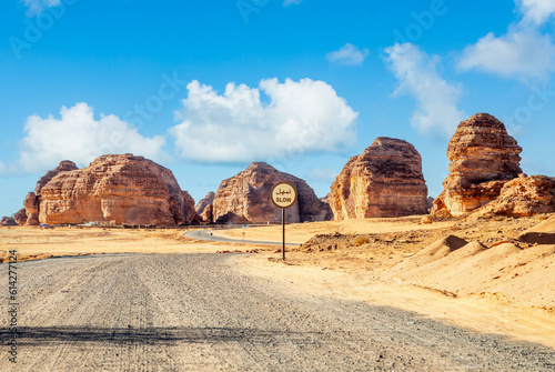 Desert road with slow sign and erosion canyon formations near Al Ula, Saudi Arabia photo