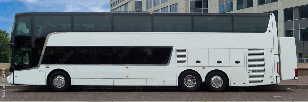 White tour bus parked in urban setting under blue sky. White tour bus parked in urban setting under blue sky.