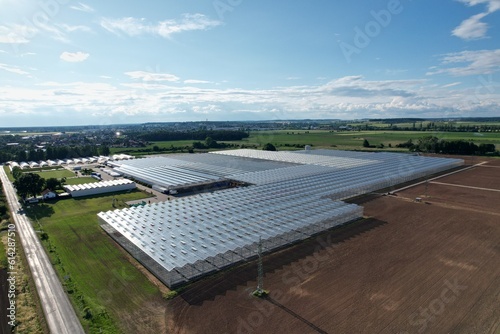 Glass greenhouses from above in sunny weather, big glass houses from aerial panorama landscape view,intensive modern agriculture in Europe