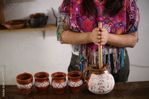 Guatemalan mayan woman making hot chocolate with molinillo blending stick photo