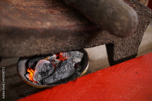 Hot burning charcoal to heat mayan grinding stone called metate photo