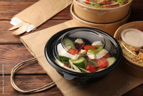 Fototapeta Naklejka Na Ścianę i Meble -  Tasty food in containers with knife and fork on wooden table