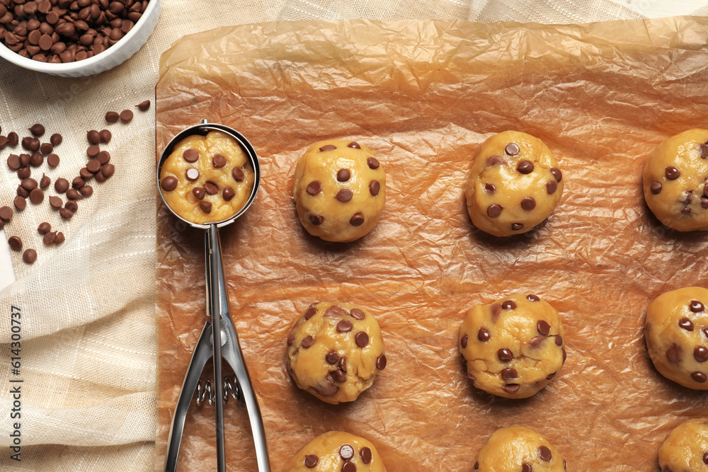 Uncooked chocolate chip cookies and scoop on parchment, flat lay Uncooked chocolate chip cookies and scoop on parchment, flat lay
