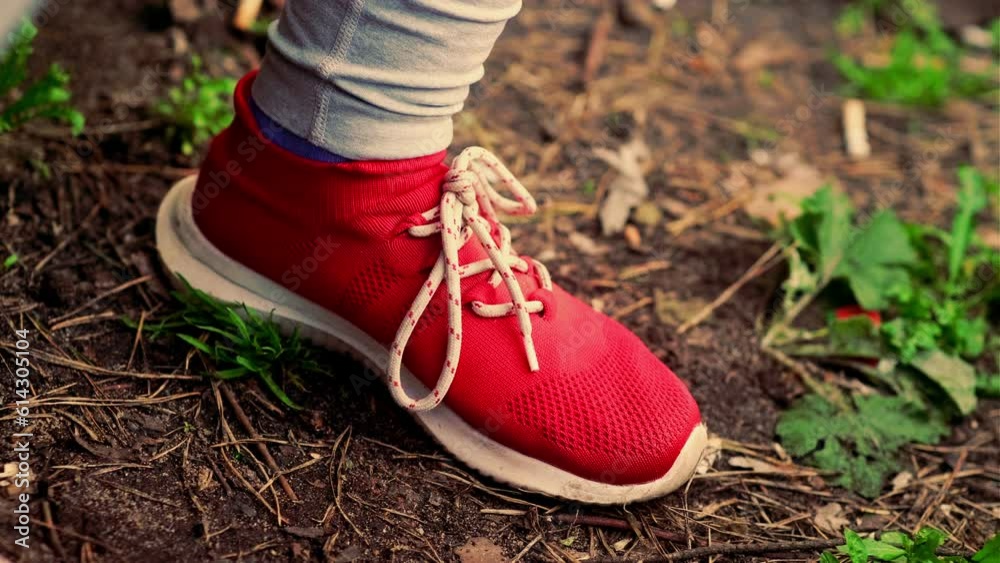 Woman's foot in red shoe. Unrecognizable person in sports shoes tapping foot on ground.