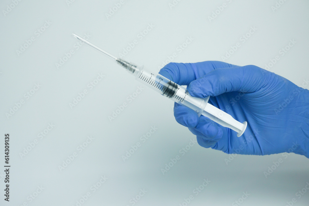 Male hand in blue gloves holding a plastic syring with liquid for injection isolated on white background. Health care, treatment concept Male hand in blue gloves holding a plastic syring with liquid for injection isolated on white background. Health care, treatment concept