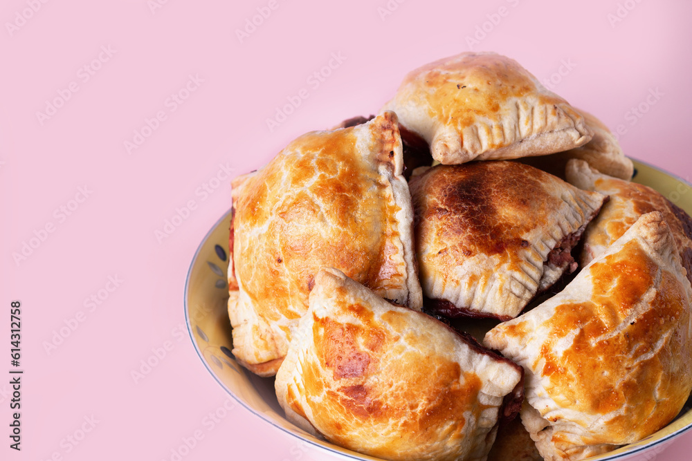 homemade buns in a large round plate, on a pink background