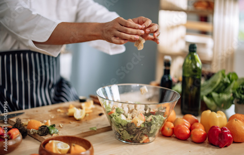 The professional master chef prepares a bowl of various types of fruit and vegetable salad with great passion and enthusiasm. Expertly mix all the ingredients and materials with care and precision.