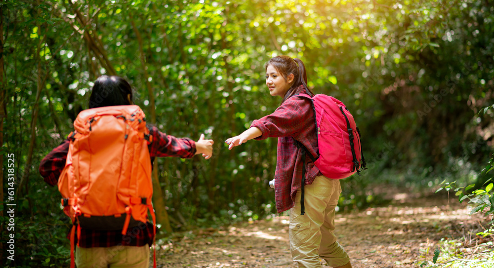 Fototapeta premium Two hikers with backpacks walking in the forest
