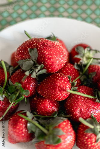 Fototapeta Naklejka Na Ścianę i Meble -  ripe strawberries on a white plate on a bright background. summer berries. seasonal fruits
