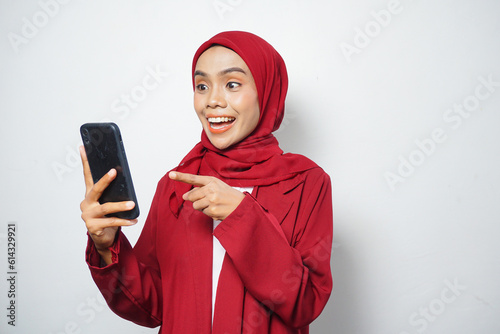 Asian Muslim businesswoman in red casual holding a smartphone isolated by a white background