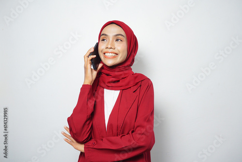 Asian Muslim businesswoman in red casual make a call isolated by a white background © rizkiwanggono