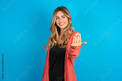 young beautiful blonde woman wearing overshirt inviting to come with hand. Happy that you came