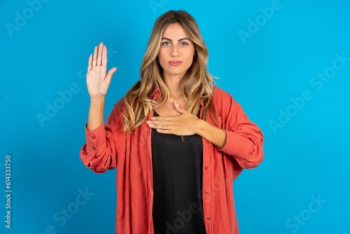 young beautiful blonde woman wearing overshirt Swearing with hand on chest and open palm, making a loyalty promise oath photo