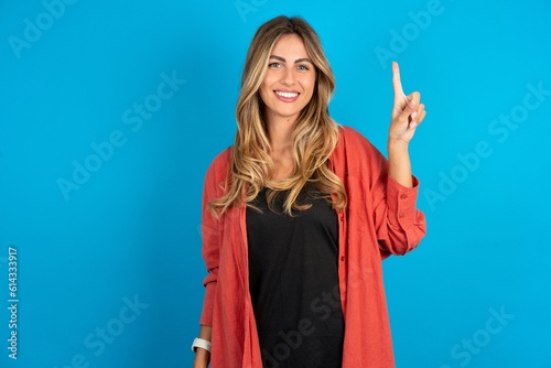 young beautiful blonde woman wearing overshirt showing and pointing up with finger number one while smiling confident and happy.