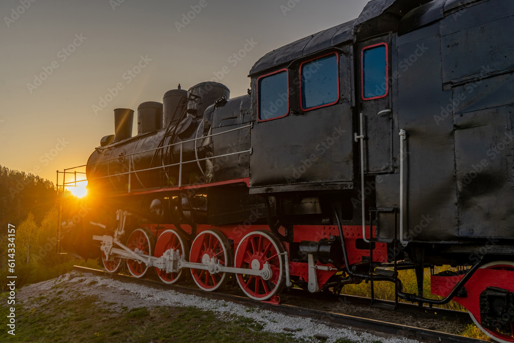 Old steam locomotive at sunset in the mountains. Retro style.