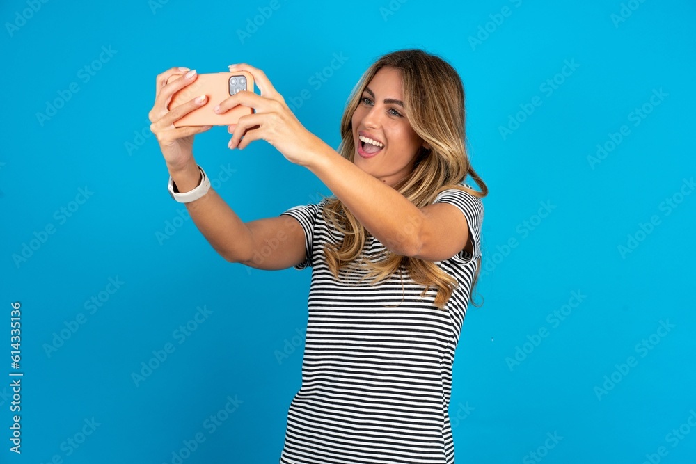 young beautiful woman wearing striped t-shirt taking a selfie to post it on social media or having a video call with friends. young beautiful woman wearing striped t-shirt taking a selfie to post it on social media or having a video call with friends.