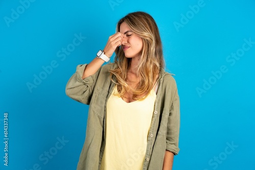 Sad young beautiful blonde woman wearing overshirt suffering from headache holding hand on her face