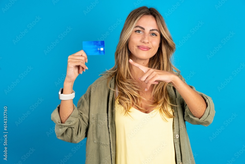 Obraz premium Photo portrait of young beautiful blonde woman wearing overshirt doing purchase with pointing finger credit bank card