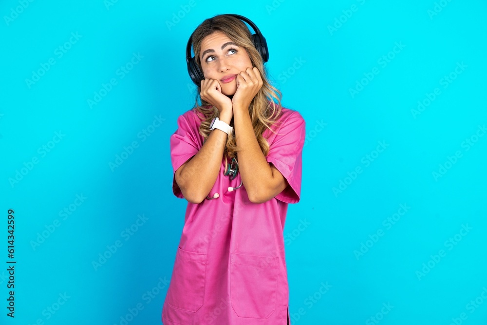 Portrait of sad Young caucasian blonde woman wearing pink uniform hands face look empty space Portrait of sad Young caucasian blonde woman wearing pink uniform hands face look empty space