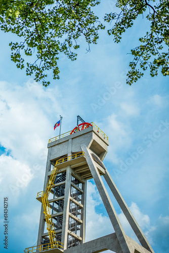 The tower of the former mine shaft against the blue sky and in the company of a tree. Currently an observation tower. Shaft President, Chorzow, Poland