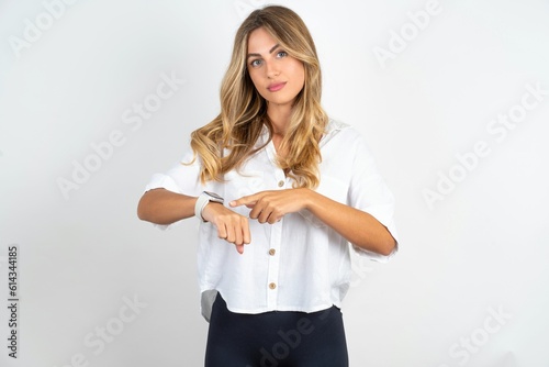 Fotografi Young caucasian business woman wearing white shirt over white background In hurry pointing to watch time, impatience, upset and angry for deadline delay