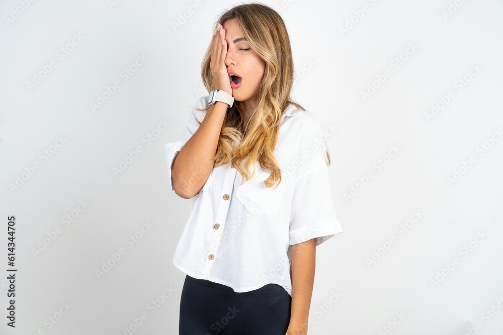 Young caucasian business woman wearing white shirt over white background Yawning tired covering half face, eye and mouth with hand. Face hurts in pain. Young caucasian business woman wearing white shirt over white background Yawning tired covering half face, eye and mouth with hand. Face hurts in pain.