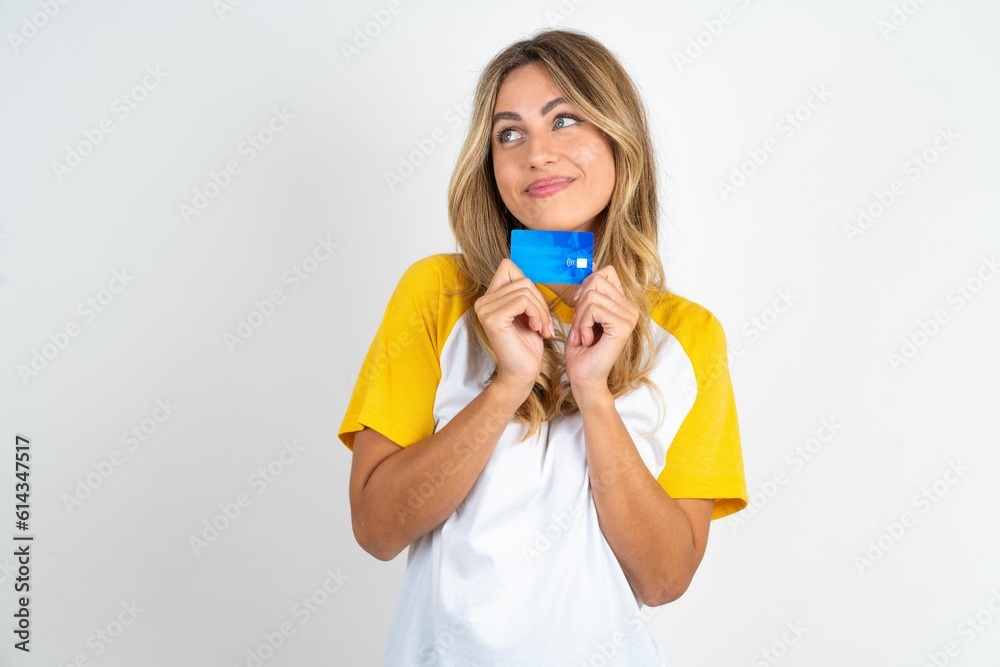 Photo of cheerful Young beautiful woman wearing football T-shirt over white background hold debit card look empty space Photo of cheerful Young beautiful woman wearing football T-shirt over white background hold debit card look empty space