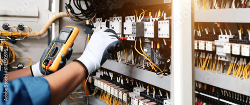 Electricity and electrical maintenance service, Engineer hand checking electric current voltage at circuit breaker terminal and cable wiring in main power distribution board. photo