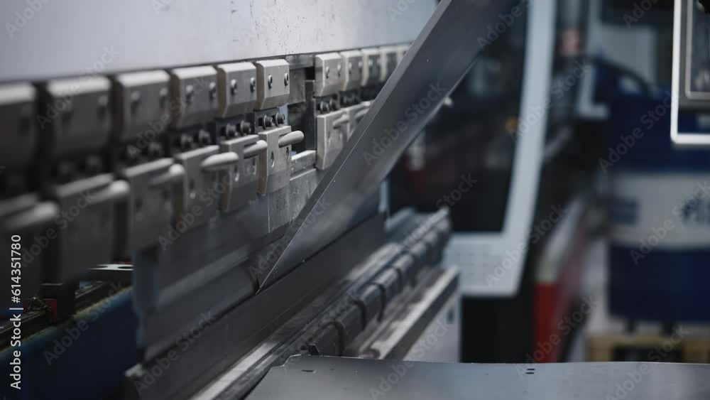 The process of bending steel sheet in production. A worker makes parts with a machine tool and a press The process of bending steel sheet in production. A worker makes parts with a machine tool and a press